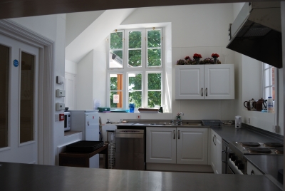 View of kitchen through hatch. Dish washer under window, heating etc. to left, stainless steel work surfaces all round